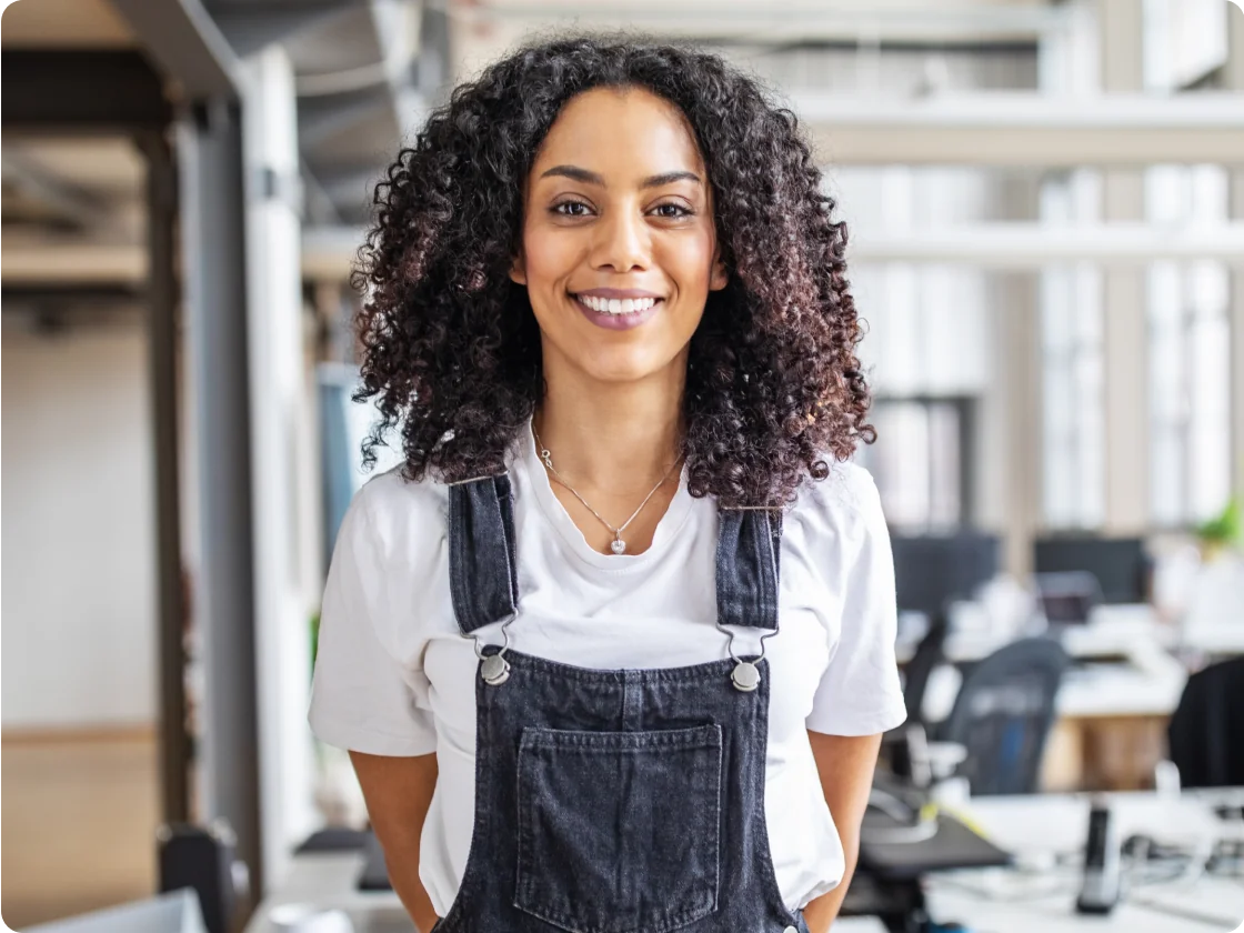 A woman in blue overalls standing in an open-plan office